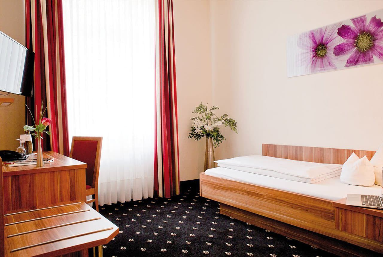 Einzelzimmer mit Blick auf Fenster und Bett